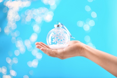 Woman holding decorative snow globe against blurred festive lights, closeup Photo of Woman holding decorative snow globe against blurred festive lights, closeup
