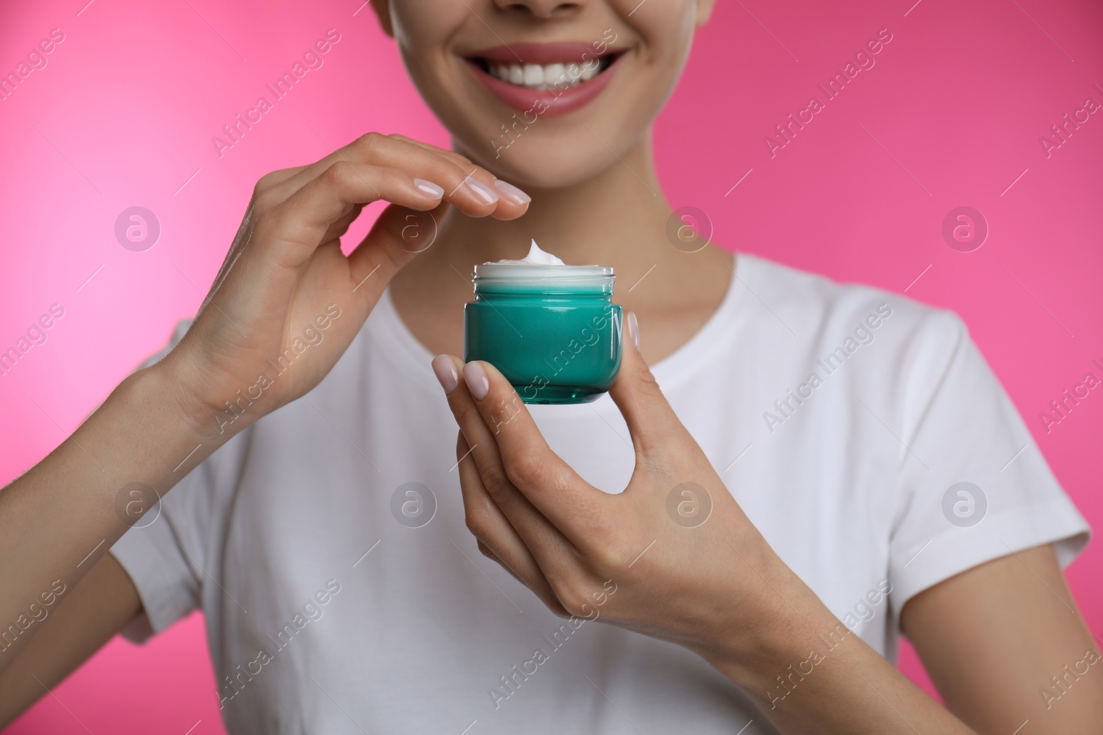 Woman holding jar of facial cream on pink background, closeup Photo of Woman holding jar of facial cream on pink background, closeup