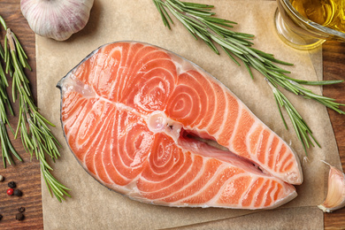 Photo of Fresh raw salmon and products on wooden table, flat lay. Fish delicacy