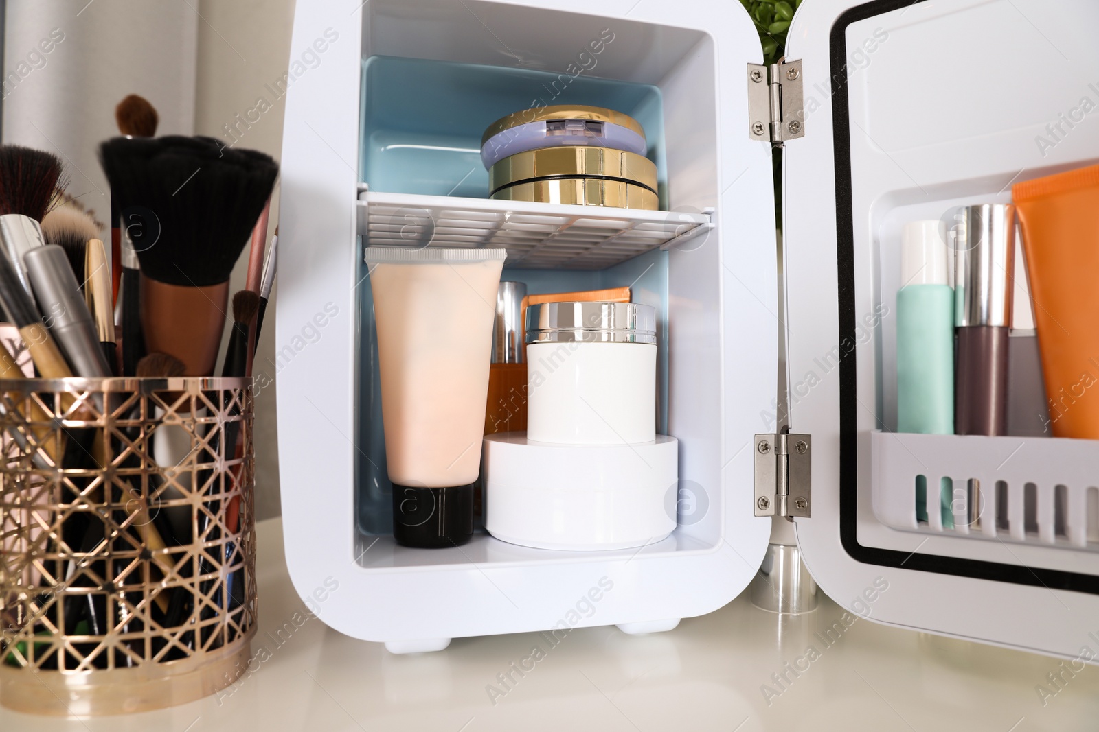 Mini fridge with cosmetic products on white vanity table, closeup Photo of Mini fridge with cosmetic products on white vanity table, closeup