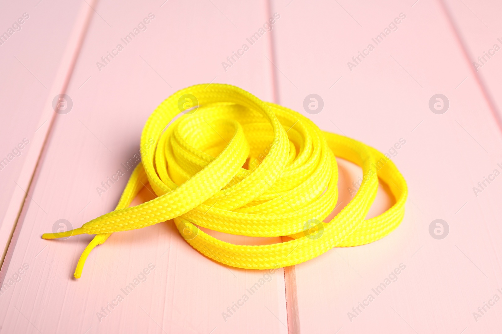 Yellow shoelace on pink wooden background. Stylish accessory Photo of Yellow shoelace on pink wooden background. Stylish accessory