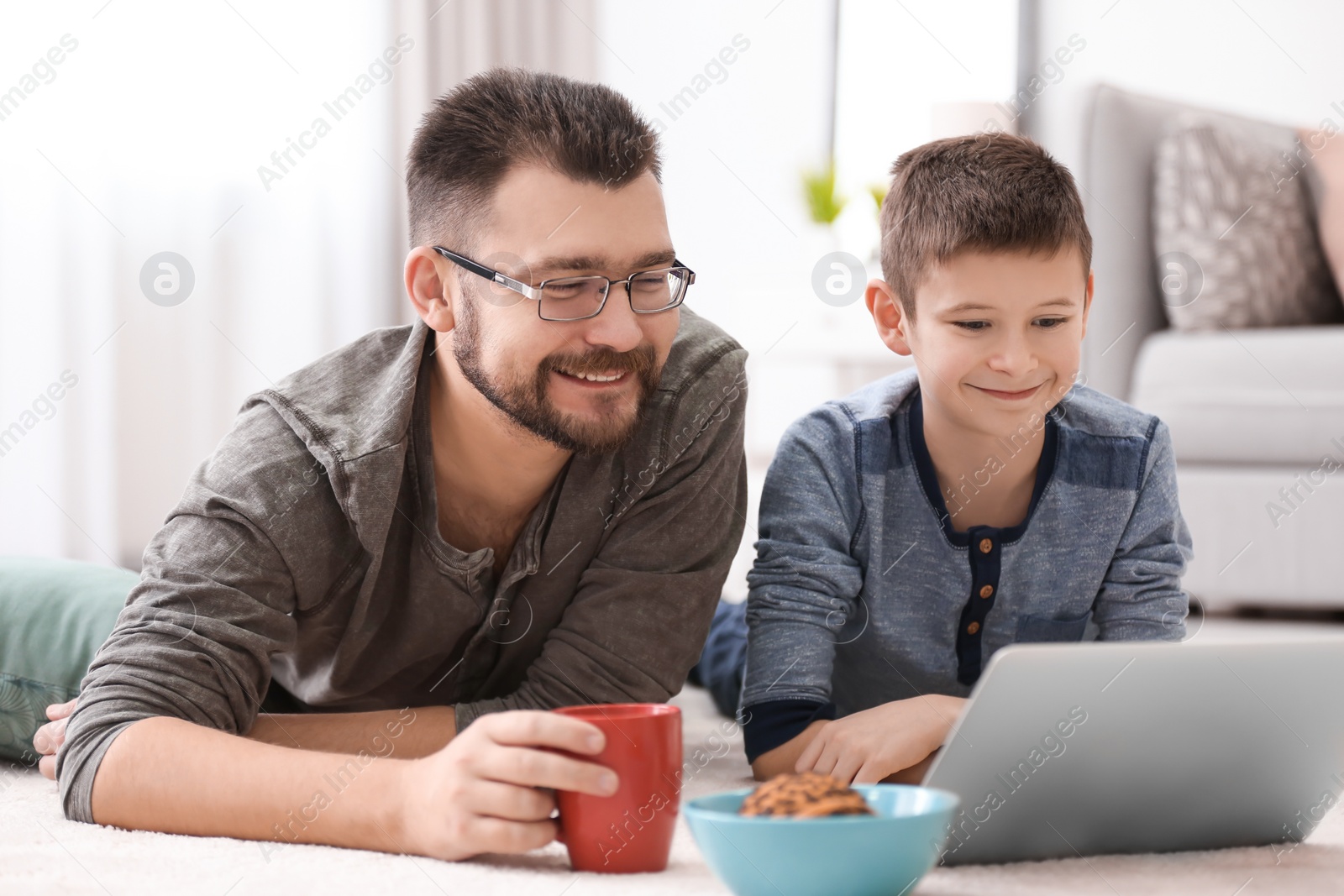 Little boy and his dad using laptop at home Photo of Little boy and his dad using laptop at home