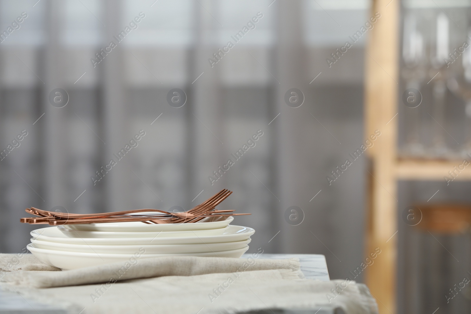 Stacked clean dishes, cutlery and towel on table indoors Photo of Stacked clean dishes, cutlery and towel on table indoors