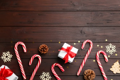 Photo of Flat lay composition with candy canes and Christmas decor on wooden table. Space for text