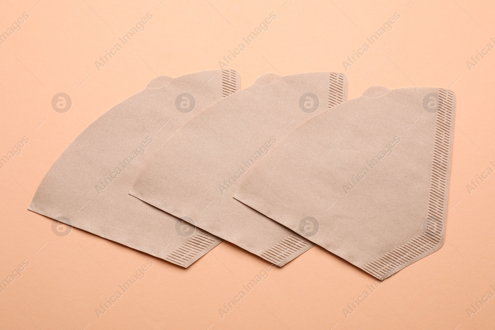 Photo of Paper coffee filters and beans on beige background, flat lay