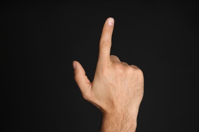 Man pointing at something on black background, closeup. Finger gesture Photo of Man pointing at something on black background, closeup. Finger gesture