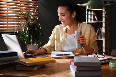 Young woman with energy drink studying at home Photo of Young woman with energy drink studying at home