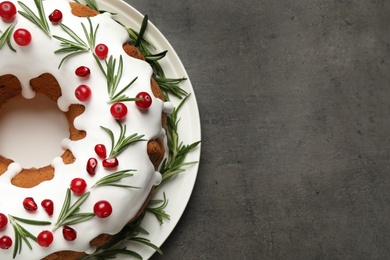 Traditional Christmas cake decorated with glaze, pomegranate seeds, cranberries and rosemary on grey textured table, top view. Space for text Photo of Traditional Christmas cake decorated with glaze, pomegranate seeds, cranberries and rosemary on grey textured table, top view. Space for text