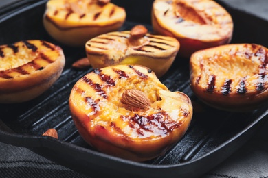 Delicious grilled peaches with almonds in pan, closeup Photo of Delicious grilled peaches with almonds in pan, closeup
