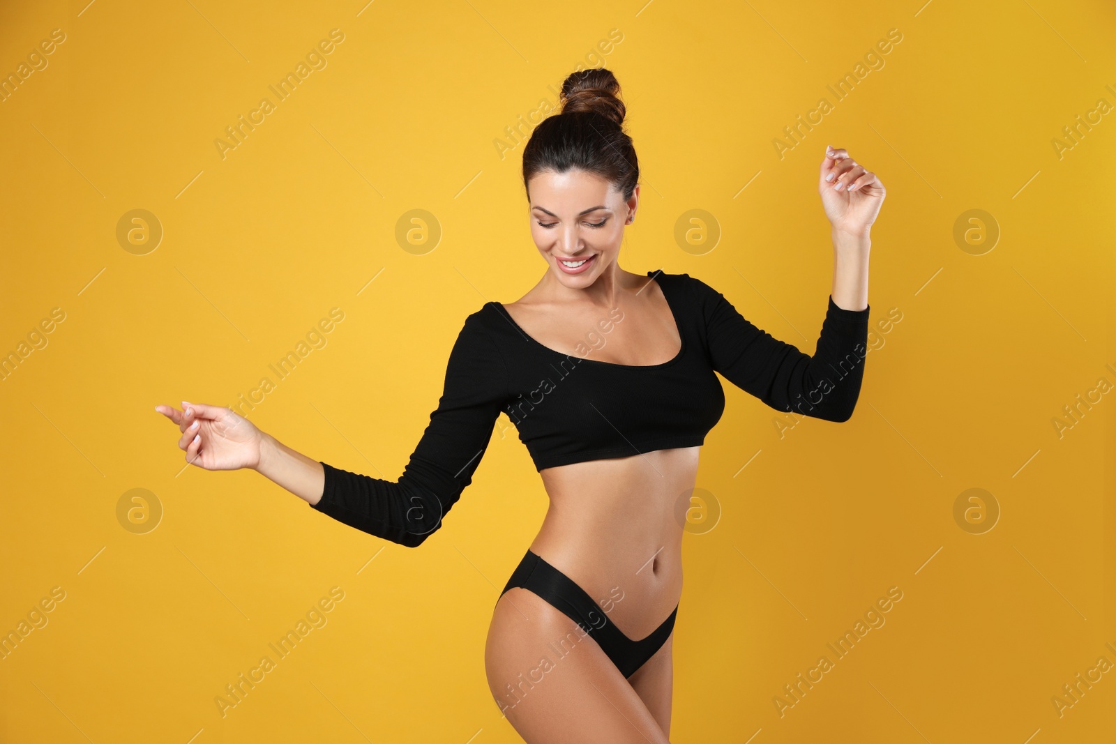 Beautiful woman in black sexy panties on yellow background Photo of Beautiful woman in black sexy panties on yellow background