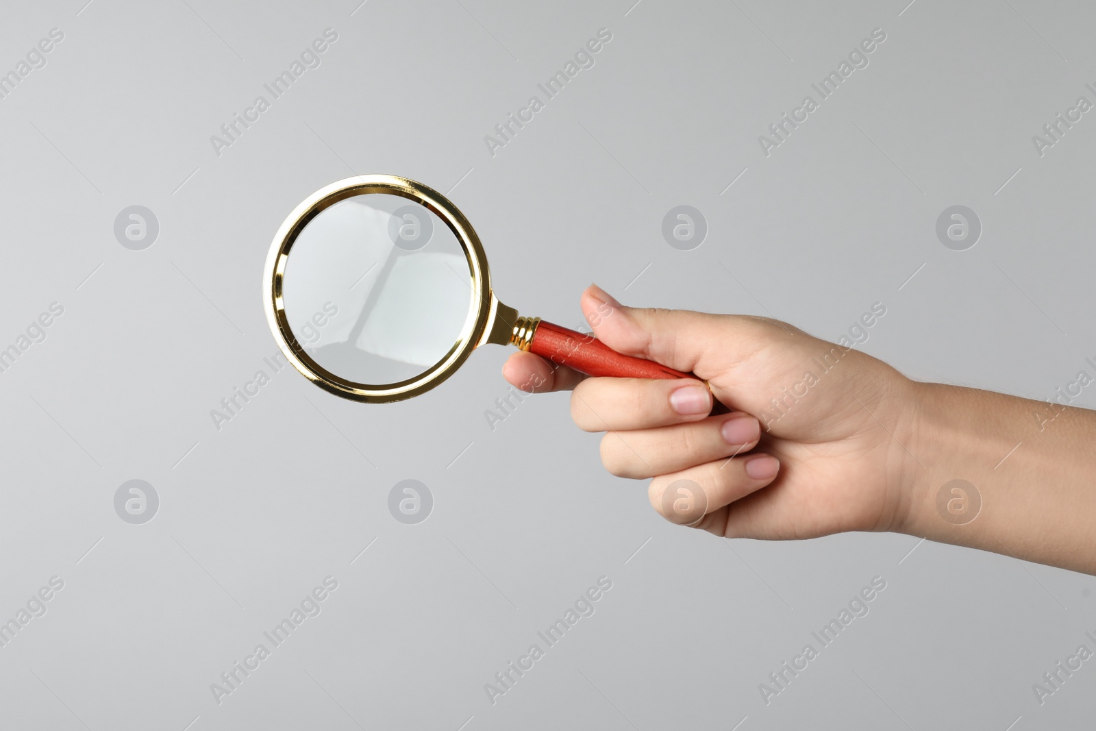 Woman holding magnifying glass on grey background, closeup. Find keywords concept Photo of Woman holding magnifying glass on grey background, closeup. Find keywords concept
