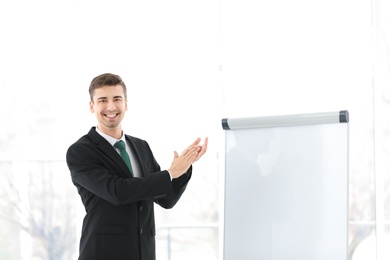 Business trainer applauding near flip chart board indoors Photo of Business trainer applauding near flip chart board indoors