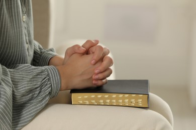 Religious woman praying over Bible indoors, closeup Photo of Religious woman praying over Bible indoors, closeup