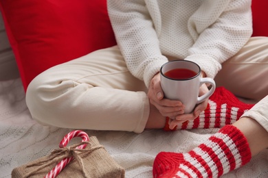 Woman relaxing with cup of hot winter drink on knitted plaid indoors, closeup. Cozy season Photo of Woman relaxing with cup of hot winter drink on knitted plaid indoors, closeup. Cozy season