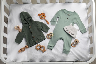 Flat lay composition with cute baby clothes and accessories on white bedsheet in crib Photo of Flat lay composition with cute baby clothes and accessories on white bedsheet in crib