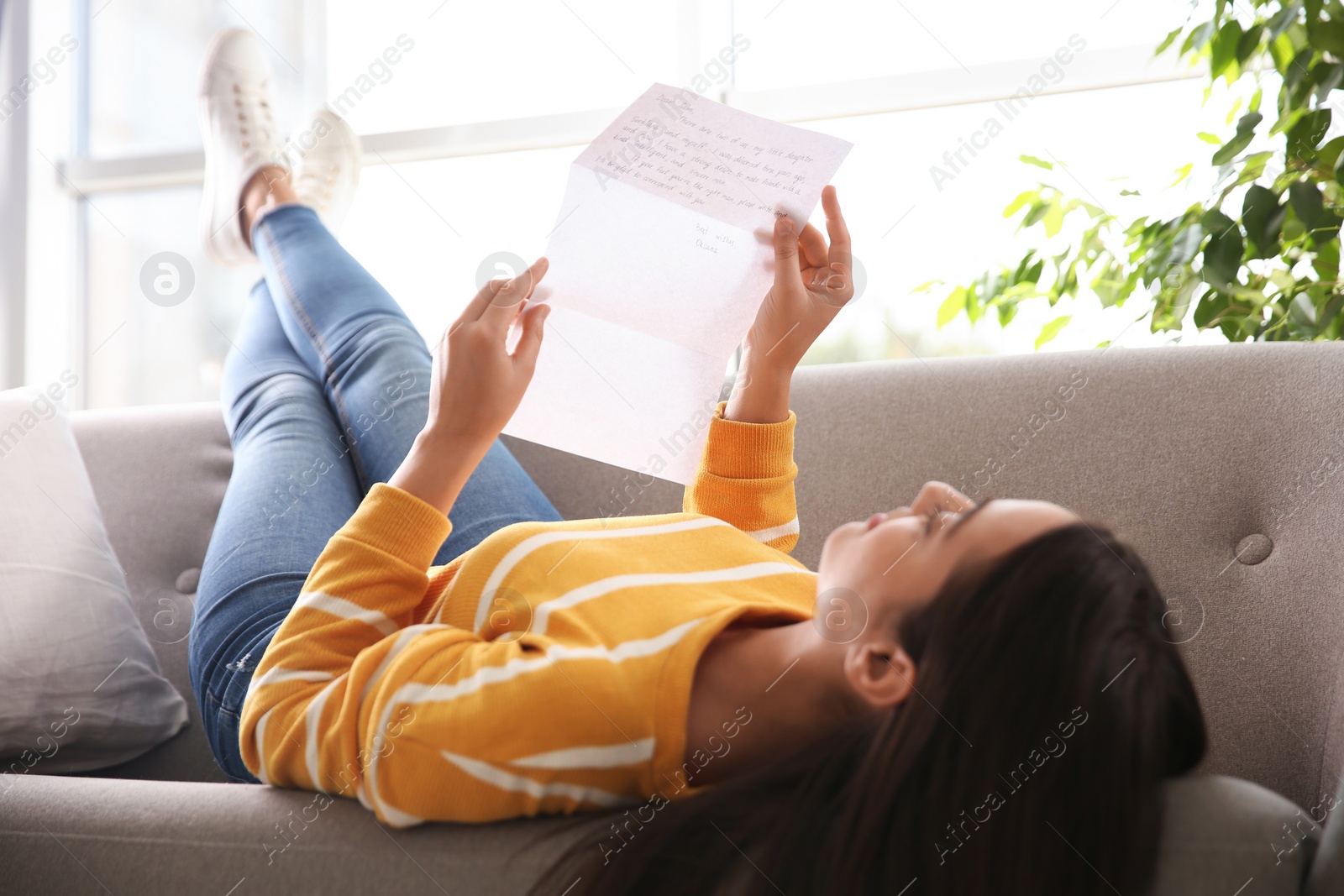 Woman reading letter on sofa at home, focus on hands Photo of Woman reading letter on sofa at home, focus on hands