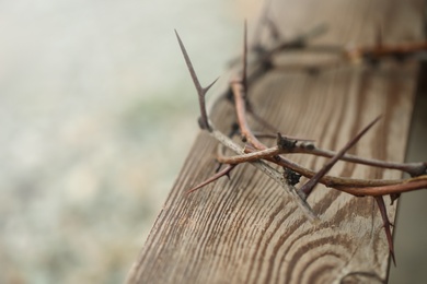 Crown of thorns on wooden plank against blurred background, closeup with space for text. Easter attribute Photo of Crown of thorns on wooden plank against blurred background, closeup with space for text. Easter attribute