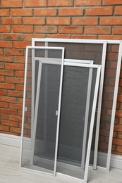 Set of window screens near brick wall indoors Photo of Set of window screens near brick wall indoors