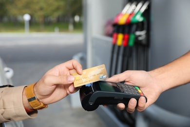 Man sitting in car and paying with credit card at gas station, closeup Photo of Man sitting in car and paying with credit card at gas station, closeup