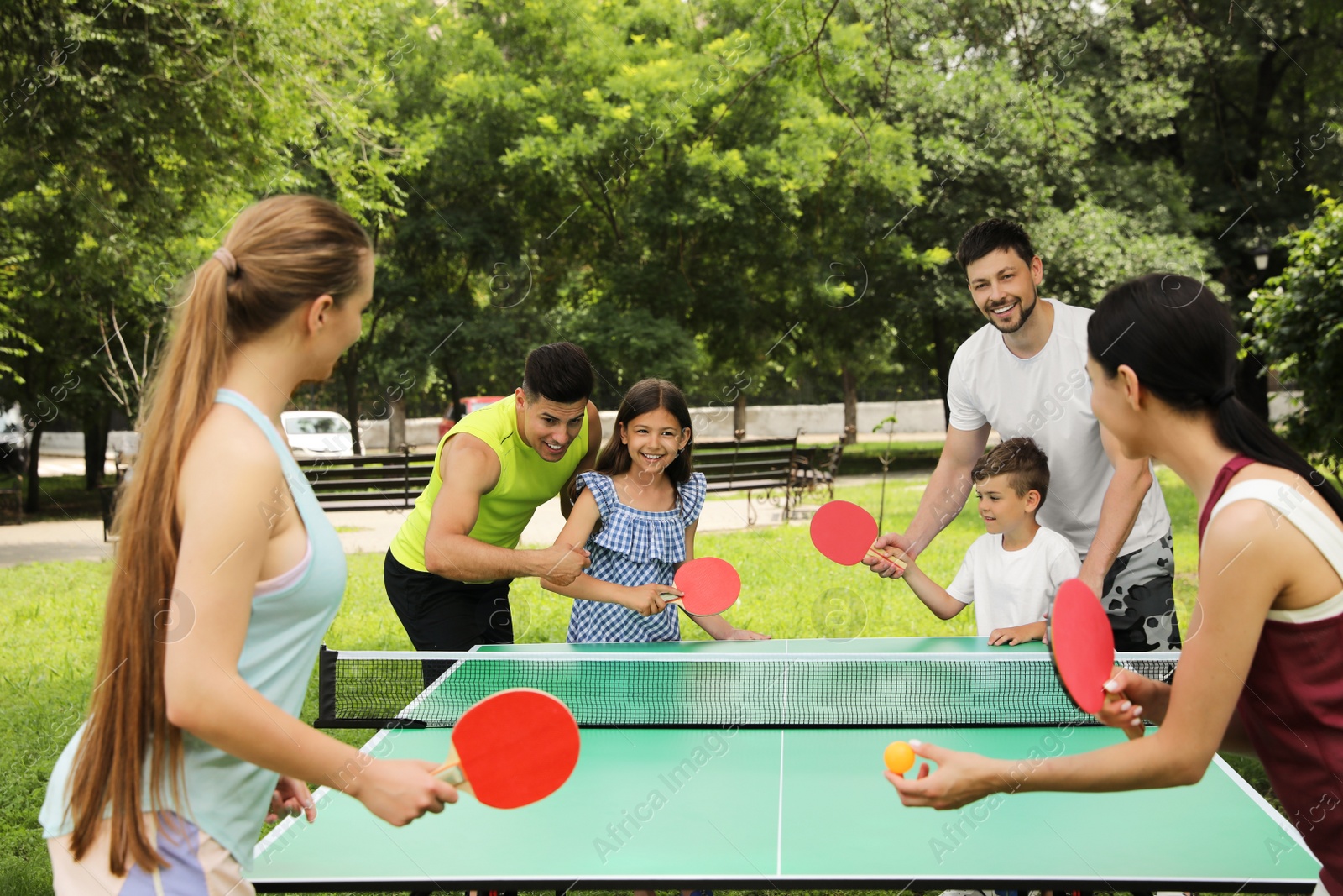Photo of Happy families playing ping pong in park