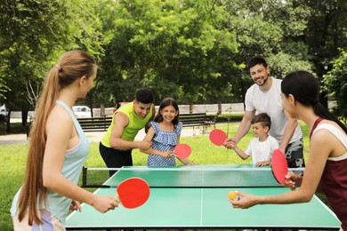 Happy families playing ping pong in park Photo of Happy families playing ping pong in park