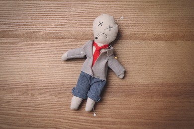 Voodoo doll pierced with pins on wooden table, top view Photo of Voodoo doll pierced with pins on wooden table, top view
