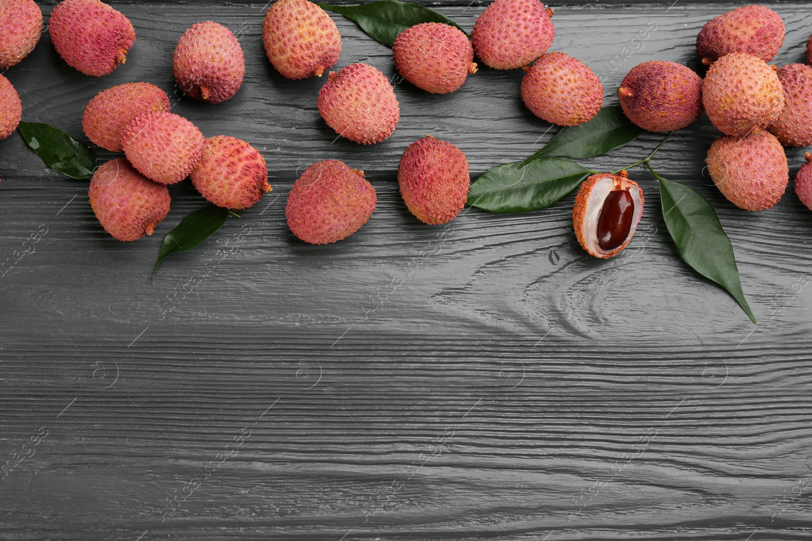 Fresh ripe lychee fruits on grey wooden table, flat lay. Space for text Photo of Fresh ripe lychee fruits on grey wooden table, flat lay. Space for text