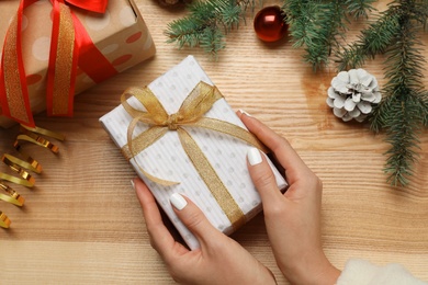 Woman with Christmas gift at wooden table, top view Photo of Woman with Christmas gift at wooden table, top view