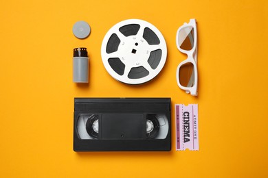 Flat lay composition with film reel and cinema ticket on orange background Photo of Flat lay composition with film reel and cinema ticket on orange background