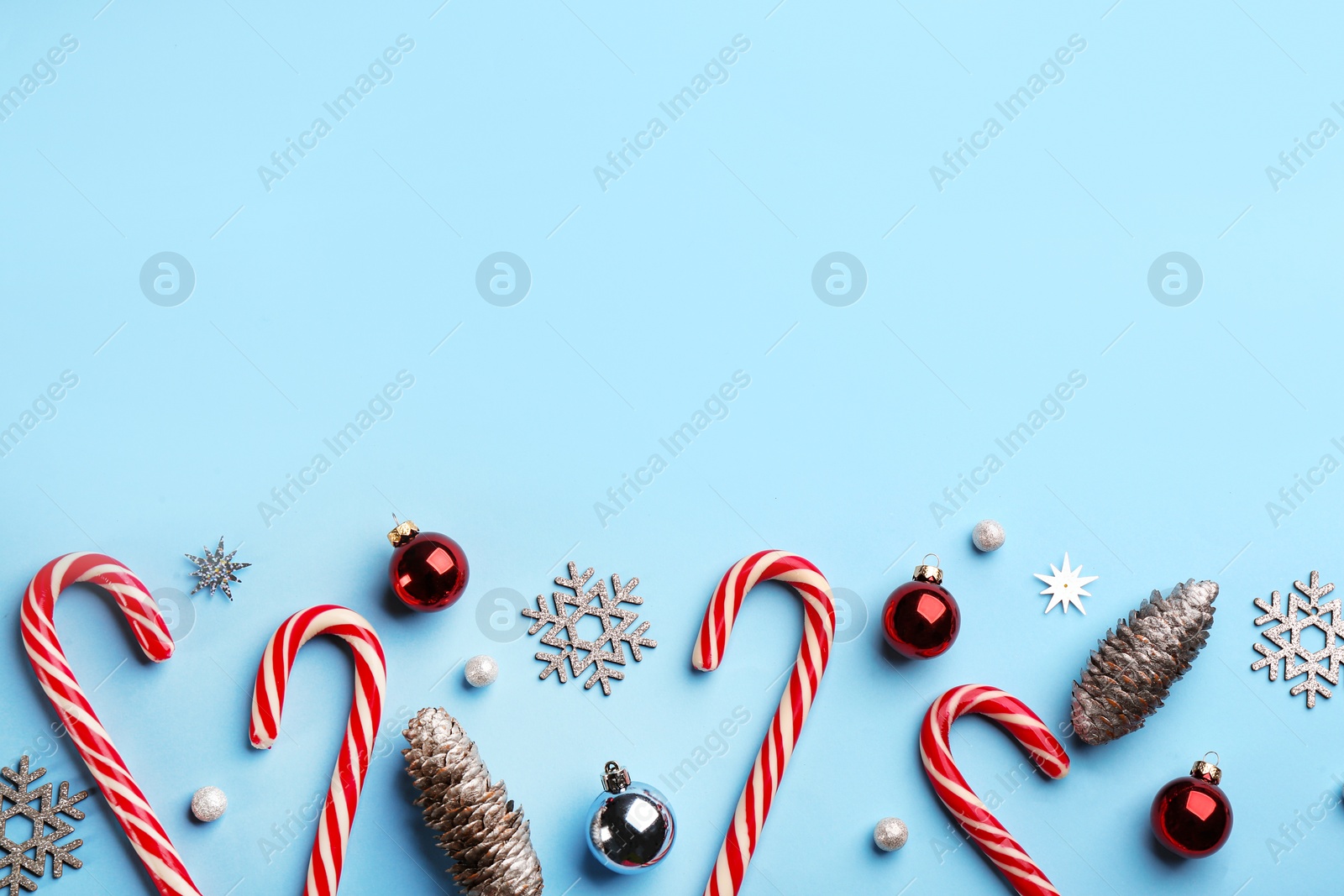 Flat lay composition with candy canes and Christmas decor on light blue background. Space for text Photo of Flat lay composition with candy canes and Christmas decor on light blue background. Space for text
