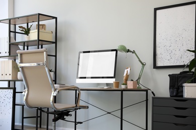 Comfortable office chair near desk with modern computer indoors Photo of Comfortable office chair near desk with modern computer indoors