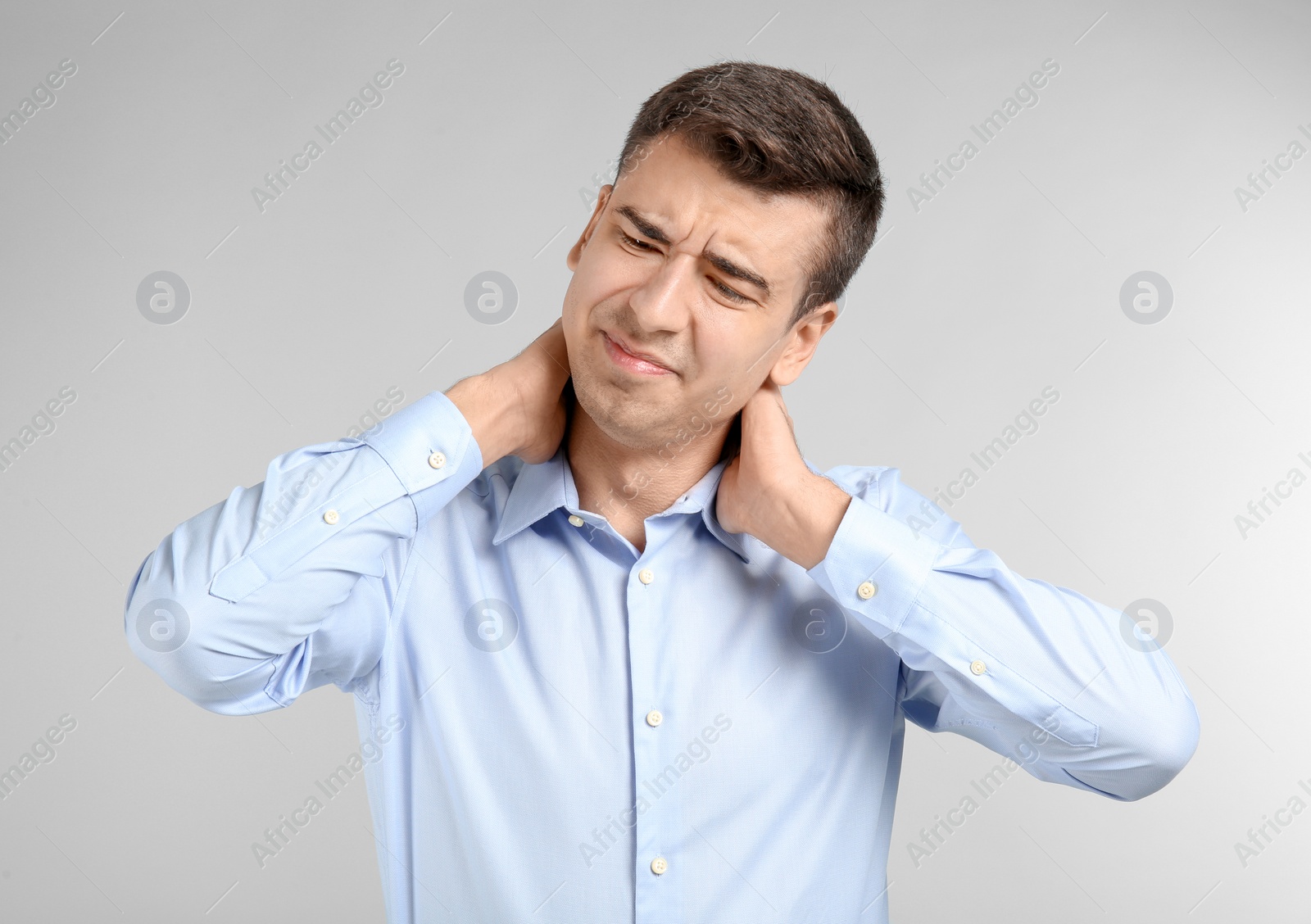 Young man suffering from neck pain on light background Photo of Young man suffering from neck pain on light background