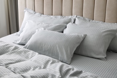 Comfortable bed with soft blanket and pillows indoors, closeup Photo of Comfortable bed with soft blanket and pillows indoors, closeup