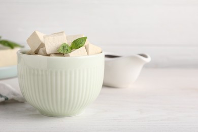 Delicious tofu with basil on white wooden table. Space for text Photo of Delicious tofu with basil on white wooden table. Space for text