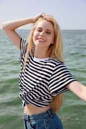 Beautiful young woman near sea on sunny day in summer Photo of Beautiful young woman near sea on sunny day in summer