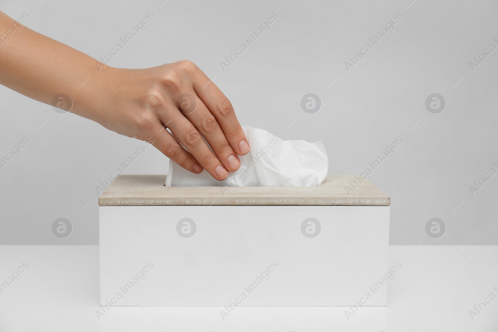 Woman taking paper tissue from holder on light background, closeup Photo of Woman taking paper tissue from holder on light background, closeup