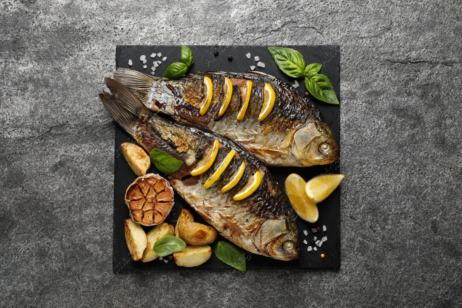 Tasty homemade roasted crucian carps served on grey table, top view. River fish Photo of Tasty homemade roasted crucian carps served on grey table, top view. River fish