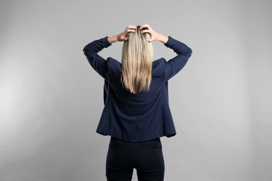 Young woman on grey background, back view Photo of Young woman on grey background, back view