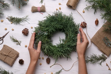 Florist with beautiful Christmas wreath of fir branches at white wooden table, top view Photo of Florist with beautiful Christmas wreath of fir branches at white wooden table, top view