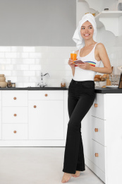Beautiful young woman with towel, phone and glass of juice in kitchen Photo of Beautiful young woman with towel, phone and glass of juice in kitchen
