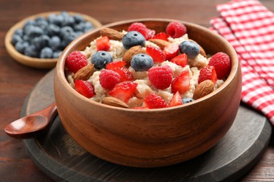Tasty oatmeal porridge with berries and almond nuts in bowl served on wooden table Photo of Tasty oatmeal porridge with berries and almond nuts in bowl served on wooden table