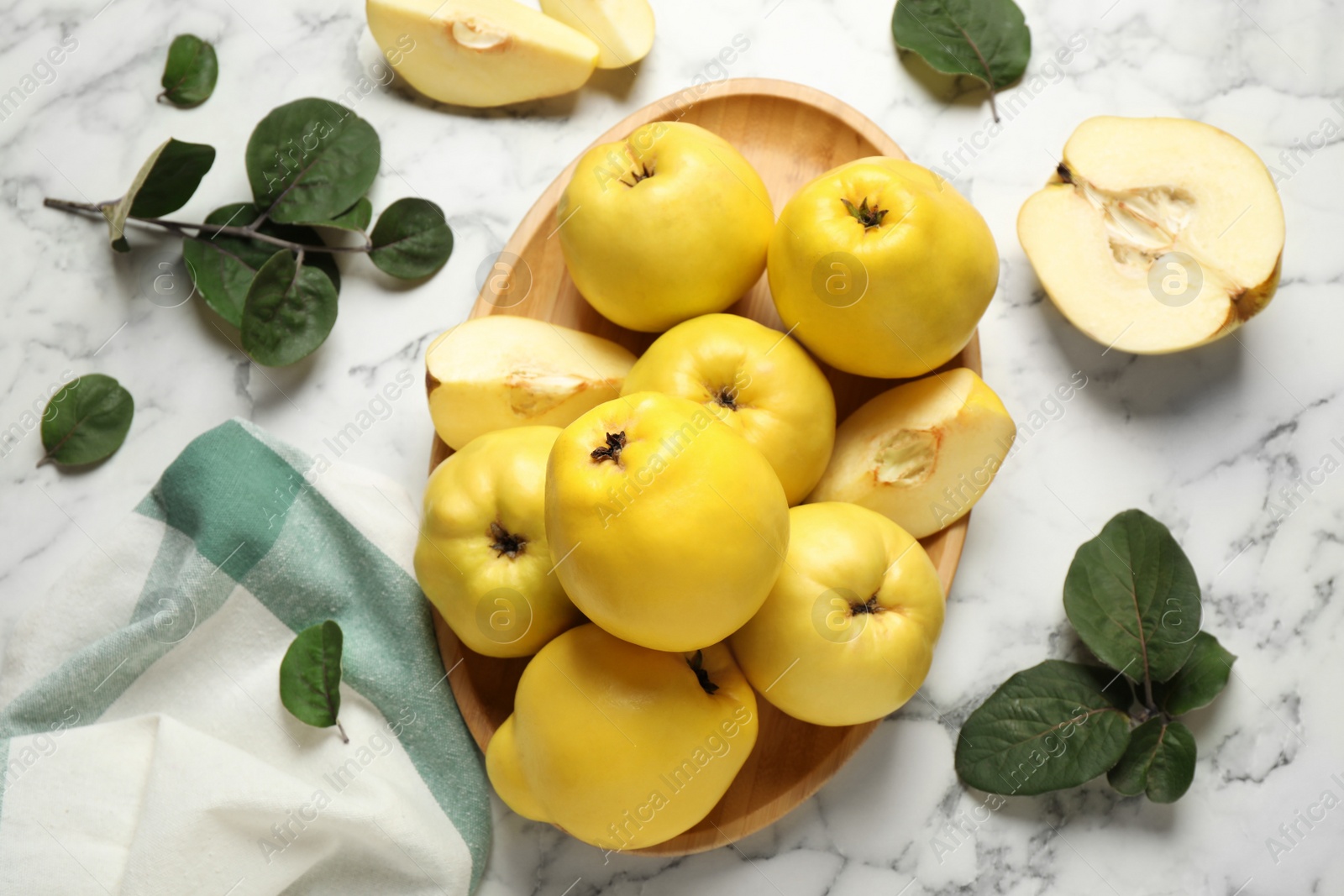 Fresh ripe organic quinces with leaves on white marble table, flat lay Photo of Fresh ripe organic quinces with leaves on white marble table, flat lay