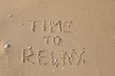 Phrase Time to Relax written on sand at beach, top view Photo of Phrase Time to Relax written on sand at beach, top view