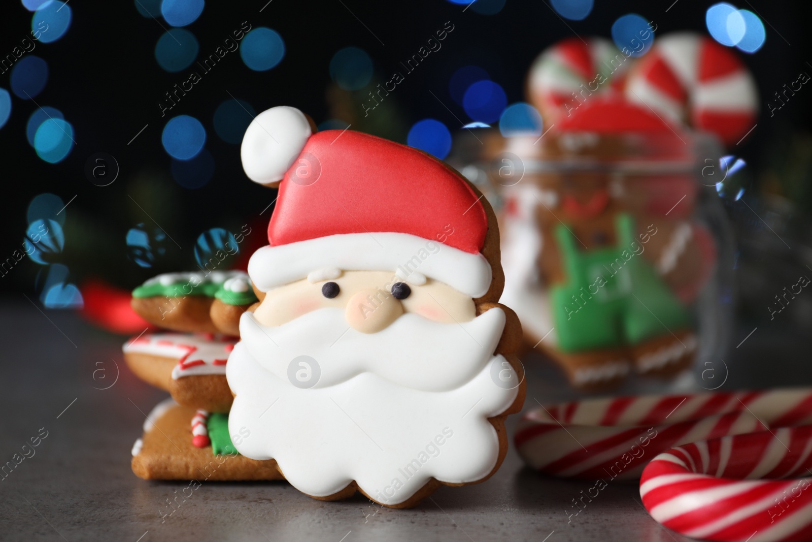 Decorated Christmas cookies on grey table against blurred festive lights Photo of Decorated Christmas cookies on grey table against blurred festive lights