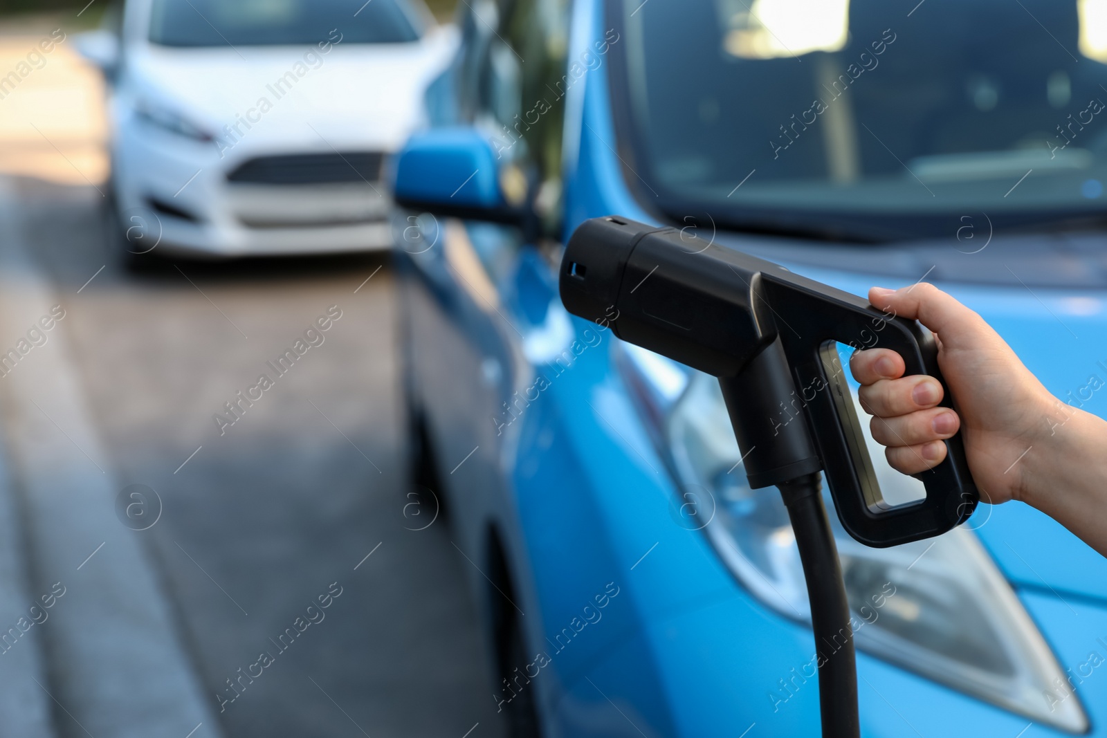 Woman holding power supply cable at electric vehicle charging station, closeup Photo of Woman holding power supply cable at electric vehicle charging station, closeup