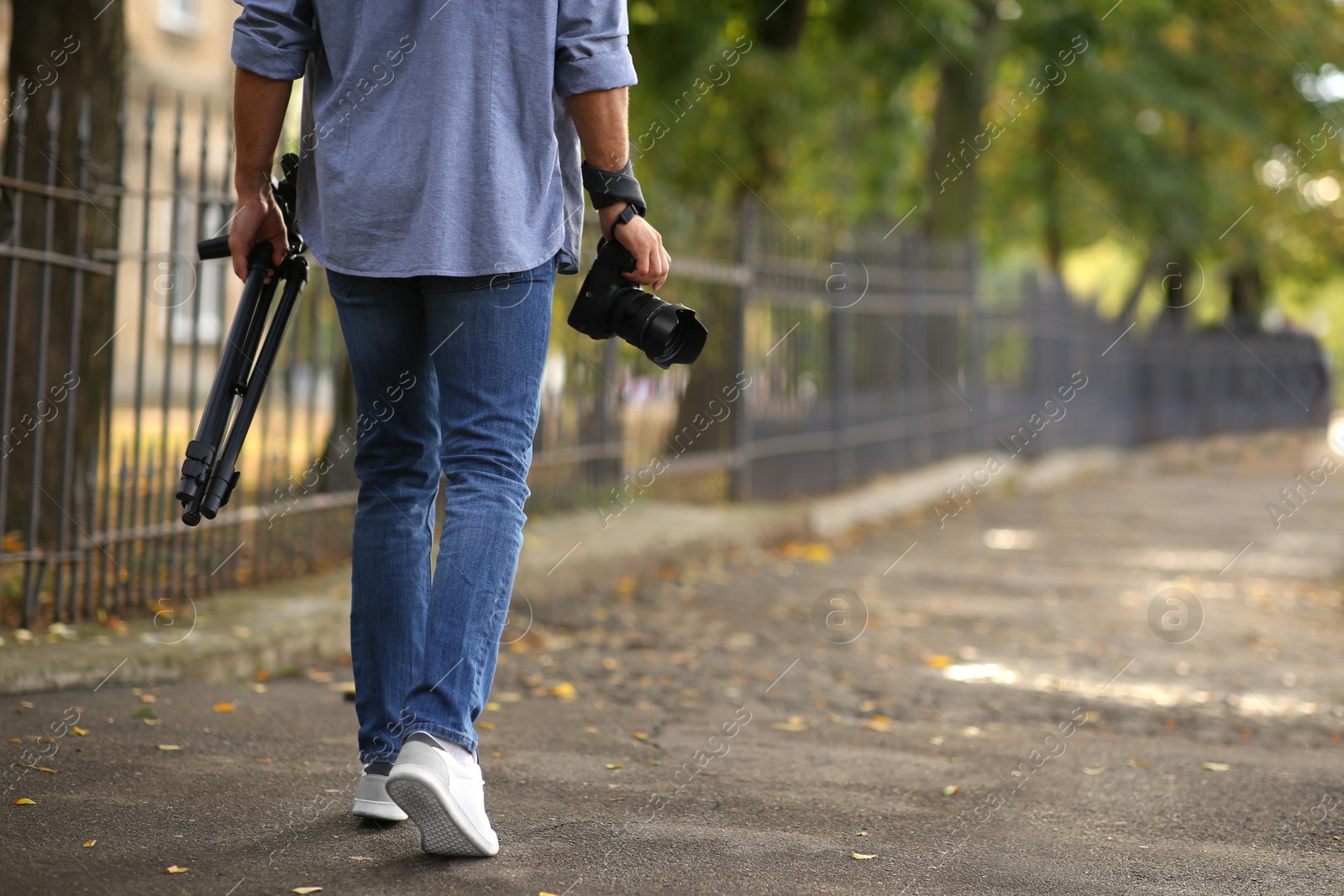 Photographer with professional camera and tripod outdoors, closeup Photo of Photographer with professional camera and tripod outdoors, closeup