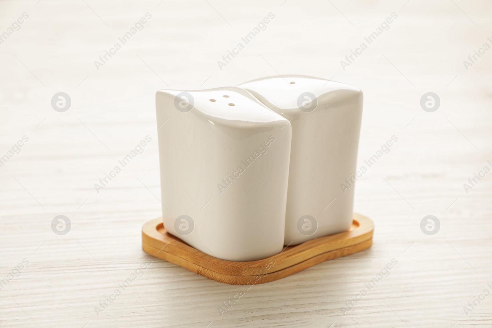 Ceramic salt and pepper shakers with stand on white wooden table, closeup Photo of Ceramic salt and pepper shakers with stand on white wooden table, closeup