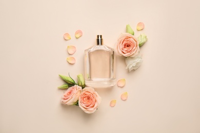 Flat lay composition with bottle of perfume and fresh flowers on beige background Photo of Flat lay composition with bottle of perfume and fresh flowers on beige background