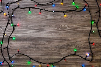 Frame of Christmas lights on wooden table, top view. Space for text Photo of Frame of Christmas lights on wooden table, top view. Space for text