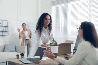 New employee unpacking box while talking with coworkers in office Photo of New employee unpacking box while talking with coworkers in office